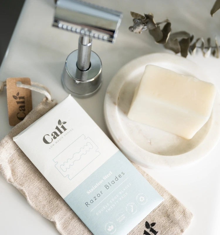 Caliwoods reusable safety razor, refill blades, and a solid shave bar on a neutral-toned surface with eco-friendly packaging. A sustainable and zero-waste shaving solution for a smooth, irritation-free experience.